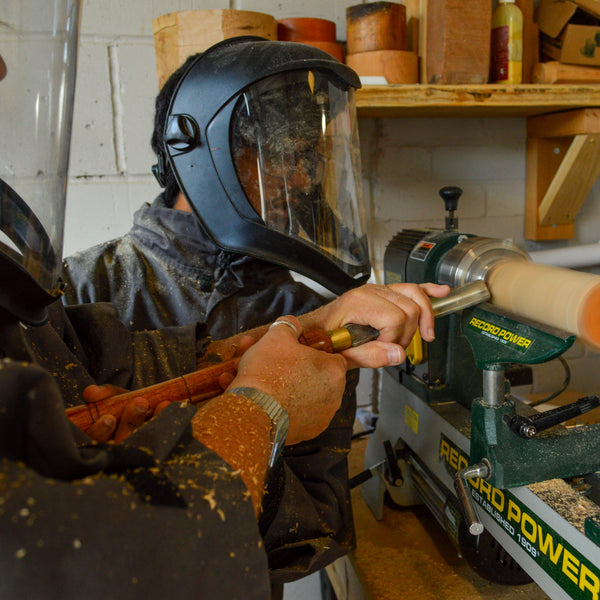 Person using a wood lathe in a workshop setting